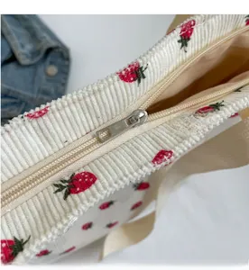 Détail macro d'un sac cabas en velours côtelé avec imprimé fraise et zip métallique lisse