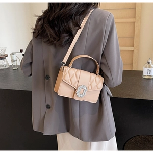 Detail of light beige quilted crossbody bag with luxury crystal square buckle on shoulder