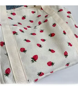 Gros plan du sac cabas en velours côtelé avec imprimé fraise et anses tissées