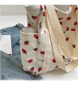 Détail du sac fourre-tout en velours blanc avec imprimé fraise et poche latérale pour parapluie