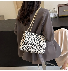 Fashionable leopard print tote bag with gold chain strap shown on a model in a modern room