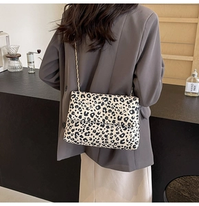 Détail du sac à rabat léopard avec chaîne dorée porté sur un blazer gris chic