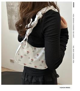 Close-up of a white floral underarm bag featuring pleated straps and Beautiful text
