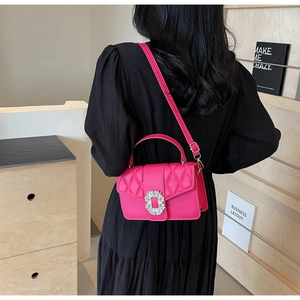 Rose pink quilted crossbody bag with rhinestone buckle worn by a model in black dress