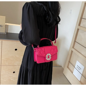 Detail of fuchsia quilted bag with crystal buckle shown as a crossbody on model