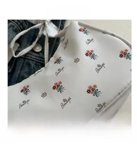 Close-up of white floral canvas bag detail featuring Beautiful text and thin strap