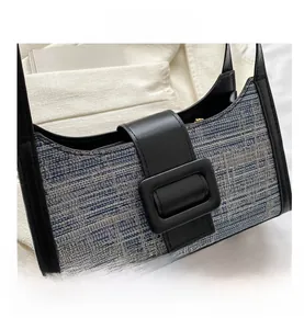 Gros plan d'un sac bandoulière en tweed bleu et blanc avec une grande boucle carrée noire