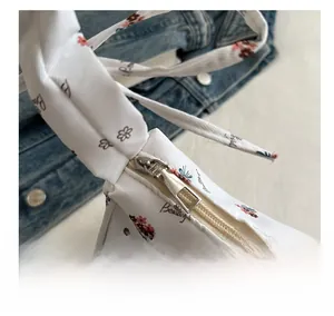 Detail view of smooth silver metal zipper and floral pattern on white fabric bag