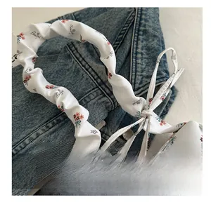 Close-up of floral tote bag with ruffled handles and a decorative bow detail