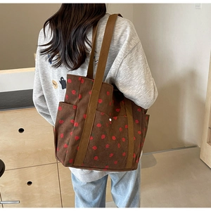 Détail d'un sac cabas en velours marron avec imprimé fraises et des bandoulières robustes