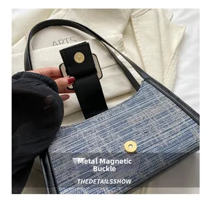 Détail du fermoir magnétique en métal doré sur le sac bandoulière tissé bleu et blanc