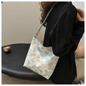 Detail of elegant gold embroidery with butterfly and bamboo patterns on light blue tote