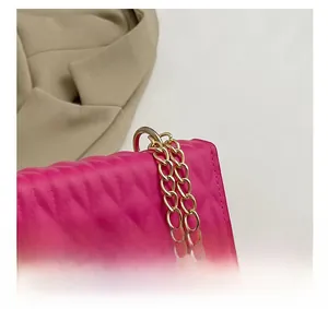 Détail macro du sac à main matelassé rose avec boucle de bandoulière en chaîne dorée