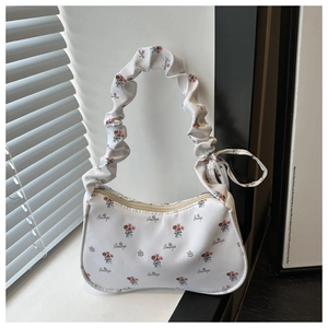 Détail du sac sous le bras fleuri montrant des fleurs rouges et une poignée froncée