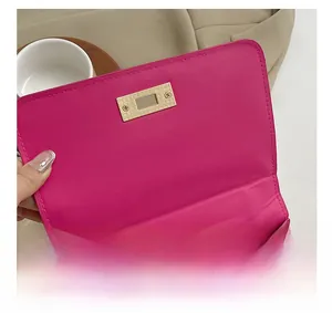 Gros plan du fermoir métallique doré sur le sac à rabat en cuir matelassé rose