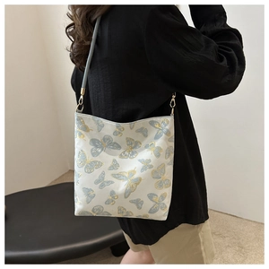 Detail of embroidered gold and blue butterflies on a white fabric shoulder bag