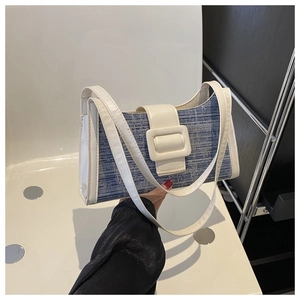 Détail du sac sous le bras en denim bleu avec bordure en cuir crème et boucle carrée