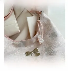 Detail of pink brocade tote featuring Chinese jacquard patterns and a silver metal bow