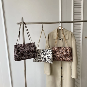 Trois sacs à bandoulière léopard de couleurs variées suspendus avec un trench-coat