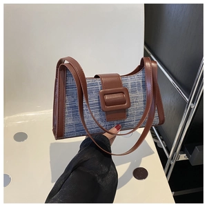Détail de la texture denim tissée bleu et blanc avec finitions en cuir marron du sac