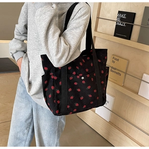 Vue détaillée du grand sac cabas en velours côtelé noir avec des motifs de fraises rouges