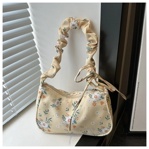 Gros plan sur le sac baguette fleuri jaune avec anse plissée et détail de nœud délicat