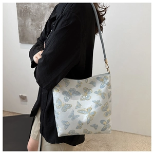 Detail of a floral canvas bucket bag with gold accents shown worn as a shoulder bag