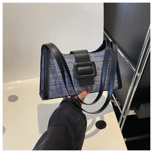 Vue détaillée de la texture tissée et de la bandoulière en cuir noir sur le sac à main