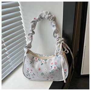 Détail d'un sac hobo floral avec poignée plissée et ruban décoratif latéral