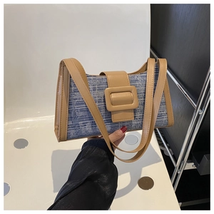 Détail du sac baguette en tweed bleu et blanc avec bandoulière en cuir brun et boucle carrée