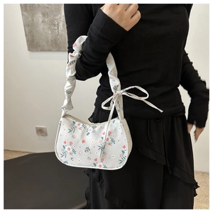 Sac bandoulière à fleurs avec plis et nœud, porté par un mannequin en style minimaliste