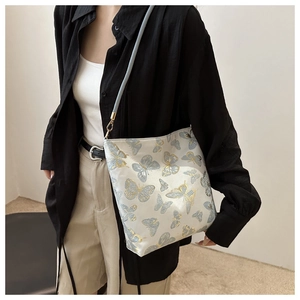 Detailed view of cream crossbody bag with gold butterfly embroidery and blue strap