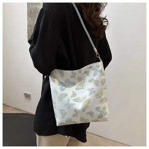 Detail of elegant white tote bag with blue butterfly patterns and gold hardware hook
