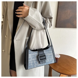 Détail du sac baguette en tweed bleu avec lanières en cuir porté par un mannequin
