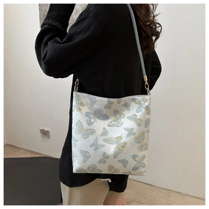 Detail of elegant gold embroidery and butterfly motifs on a cream shoulder bag