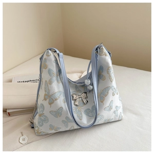 Detail of light blue butterfly embroidery and silver metal bow on a silk texture tote bag
