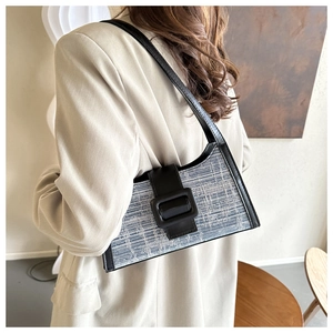 Détail d'un sac baguette en tweed bleu et blanc avec bandoulière en cuir noir