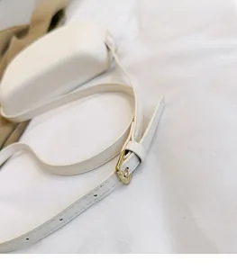 Detailed shot of cream leather bag with adjustable gold buckle strap and fine stitching