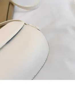 Detail view of the soft ivory white leather texture and flap cover of the shoulder bag