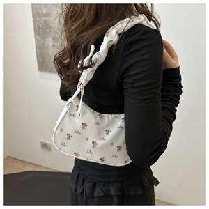 Détail du sac sous l'aisselle à fleurs blanches avec bandoulière plissée