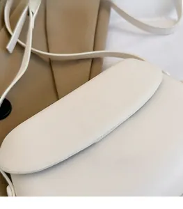 Detail shot of the white minimalist faux leather handbag showing fine texture and flap