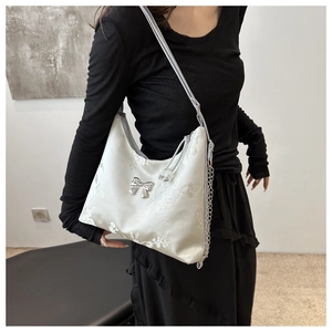 Close-up of cream hobo bag featuring floral relief pattern and silver bow detail