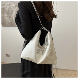 Close-up of floral embroidery and silver bow detail on a cream white satin Hobo bag