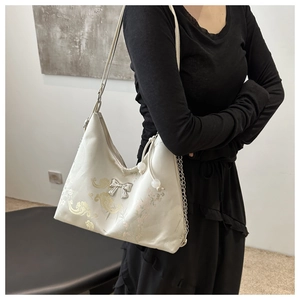 Detail of jacquard tote with silver butterfly accessory and metal chain shoulder strap