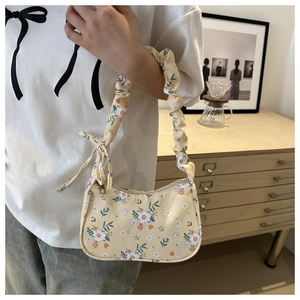Close-up of floral print underarm bag featuring a ruffled handle and bow detail