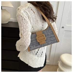Détail du sac à bandoulière en denim et cuir avec boucle sur l'épaule du mannequin