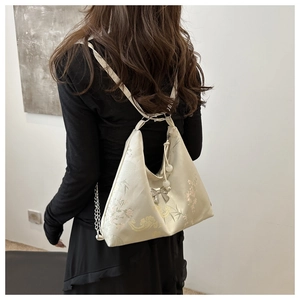 Detail of beige silk tote with traditional jacquard patterns and bow metal charm