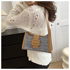 Détail du sac baguette tissé bleu et gris avec garniture en cuir brun et boucle géante