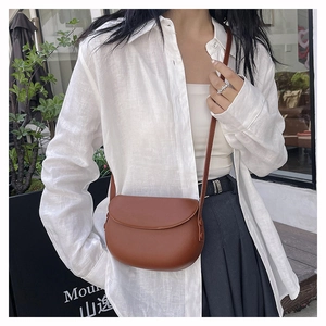 Brown leather saddle bag with shoulder strap styled on a model for a chic daily outfit