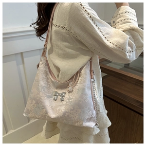 Detail of pink floral jacquard tote with silver bow pendant and elegant chain strap